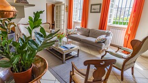 A living room with a sofa, armchairs, a coffee table, and a potted plant.