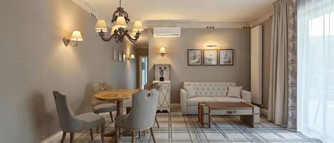 Una sala de estar moderna con comedor, que incluye una araña, un sofá y una mesa de centro.