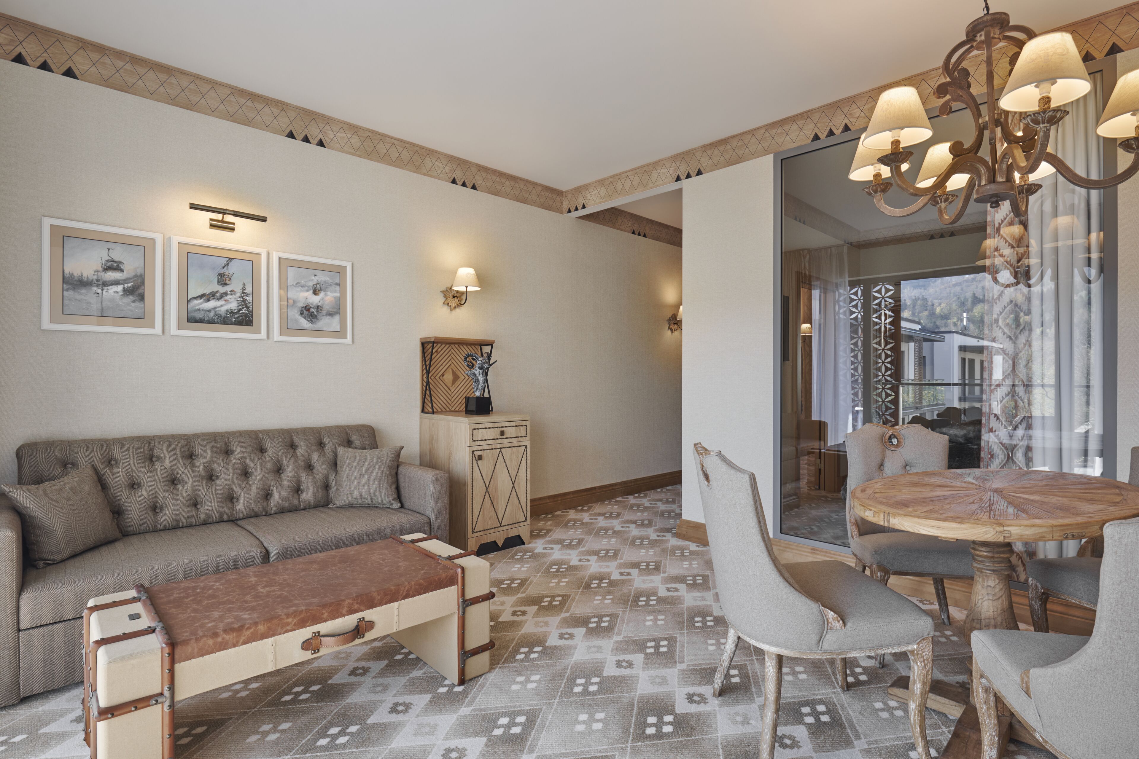 A living room with a sofa, a bench, a wooden cabinet, and a round table with chairs. There are wall-mounted lights and framed pictures on the wall.