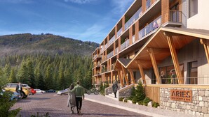 Un edificio moderno con fachada de piedra y balcones de madera, identificado como “ARIES RESIDENCE & SPA”.