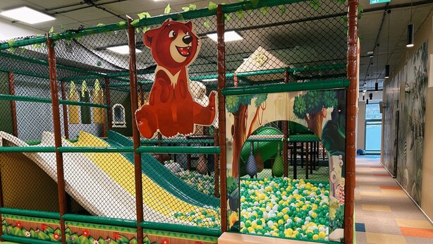 Ein Kinderspielbereich mit Rutsche, Bällebad und einer großen Bär-Dekoration.