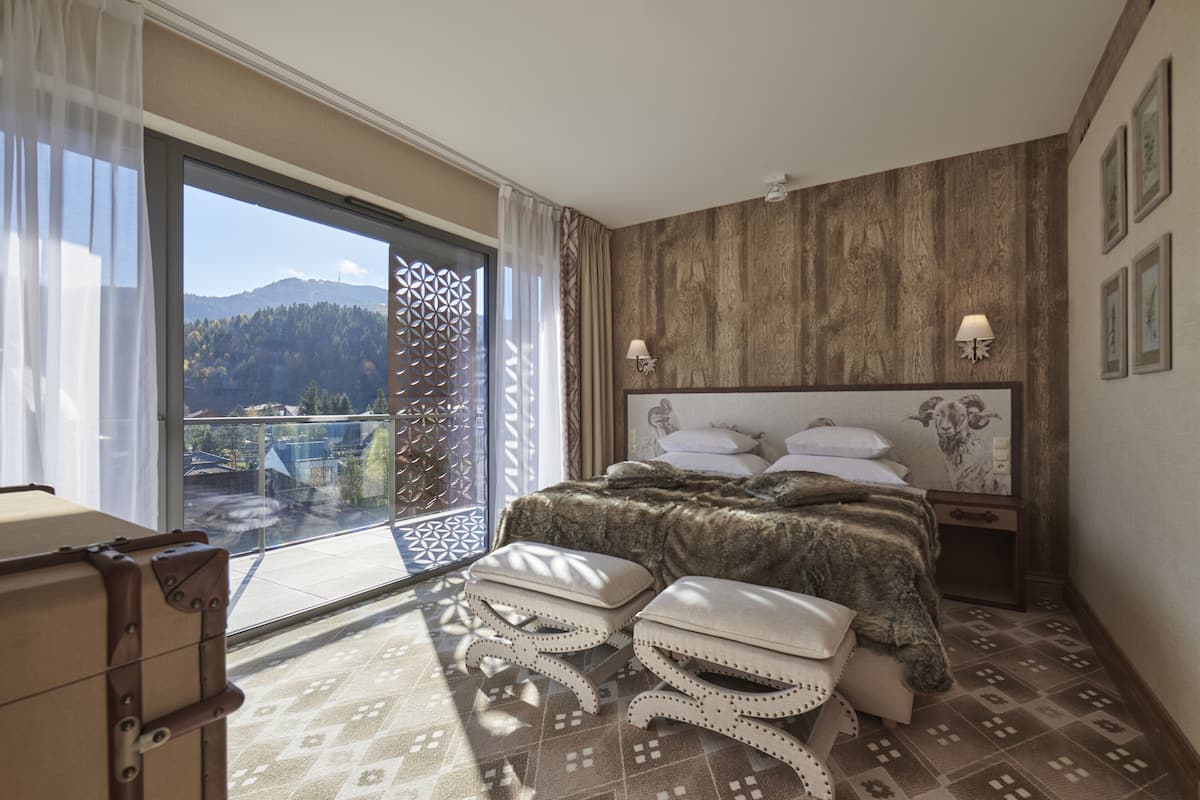 Un dormitorio con un amplio ventanal, una cama con cabecero estampado y vistas al exterior.