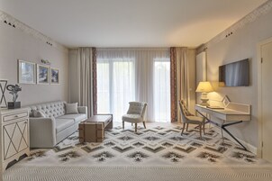 Una camera d'albergo con divano, poltrona, scrivania e tappeto decorato.