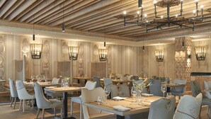 Un comedor espacioso con varias mesas y sillas, elegantes lámparas y techo de madera.