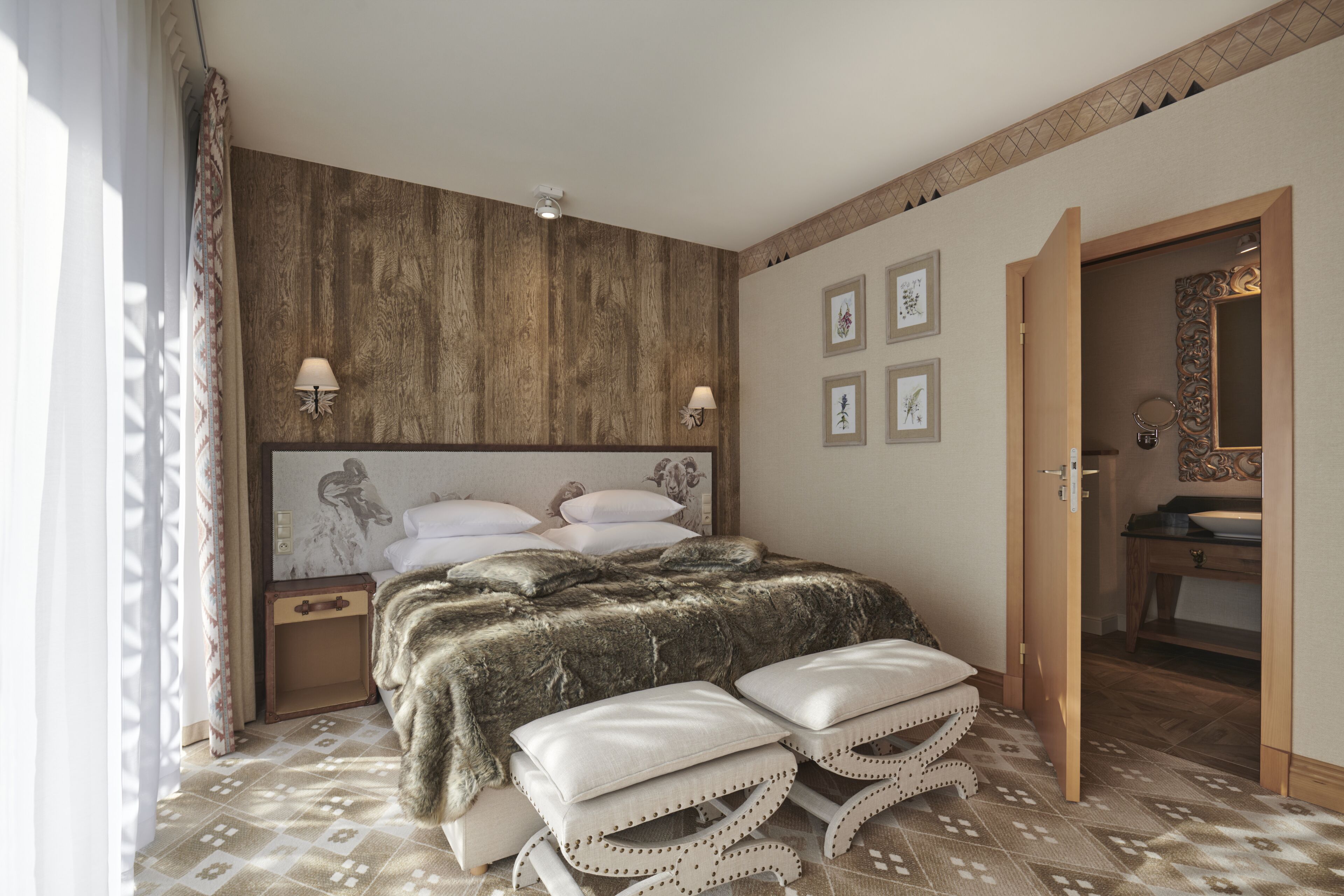 Quarto com cama grande, duas mesas de cabeceira, cabeceira, painel de parede em madeira, piso estampado e banheiro visível por uma porta aberta.