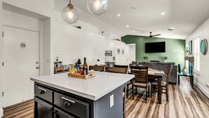Een moderne keuken met een centraal eiland, houten vloeren en hanglampen.