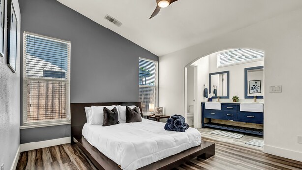 Een moderne slaapkamer met een groot bed, houten vloeren en uitzicht op de badkamer.