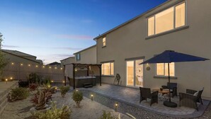 A residential backyard with a hot tub, outdoor seating, and string lights. - New South Reno Home with Hot Tub (Reno)