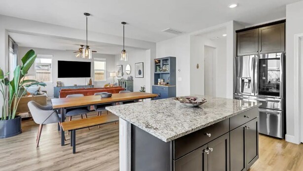 A modern kitchen with a granite countertop, stainless steel appliances, and a dining area with a wooden table and benches. - New South Reno Home with Hot Tub (Reno)