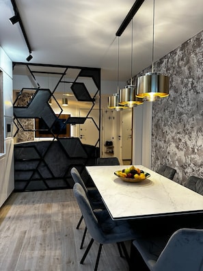 A modern dining area with a marble table, black chairs, a fruit bowl, and pendant lighting. - Alezzi Infinity Resort & Spa (Navodari)