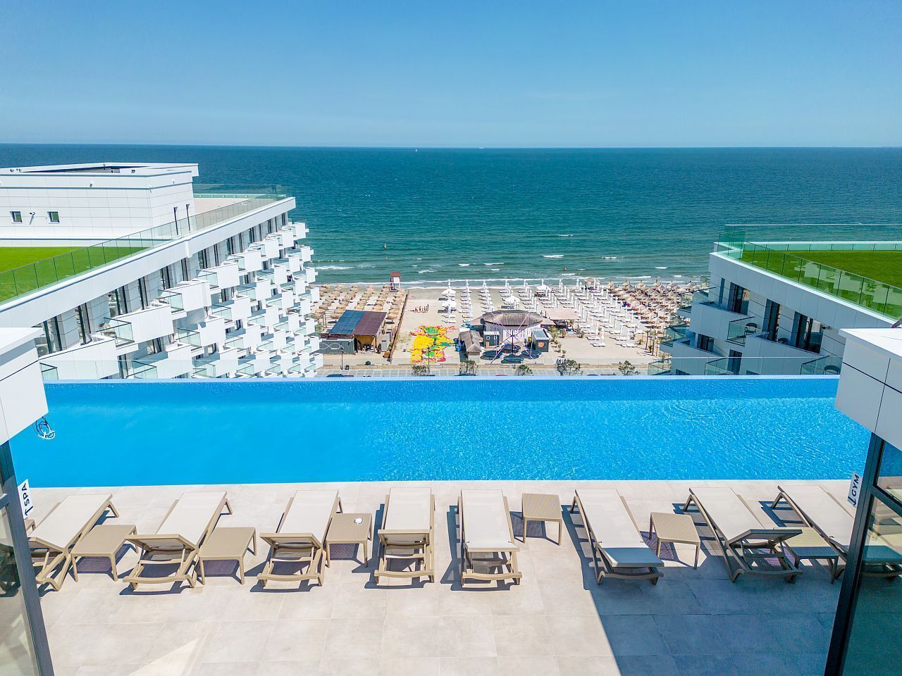 Ein Poolbereich eines Hotels mit Blick auf das Meer, Liegestühle und ein Pool.