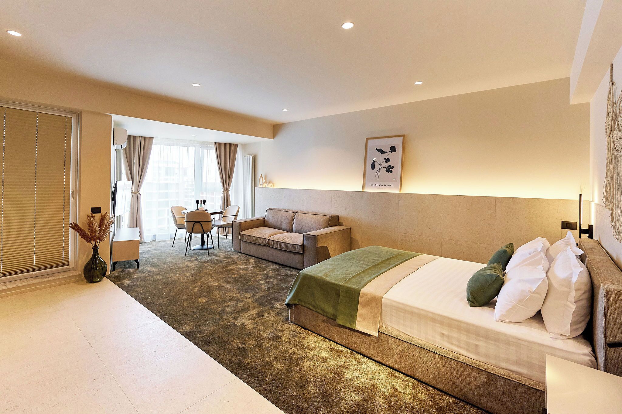 Et hotelværelse med seng, sofa, spisebord og stol.