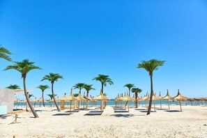 A beach with palm trees and thatched umbrellas. - Alezzi Infinity Resort & Spa (Navodari)