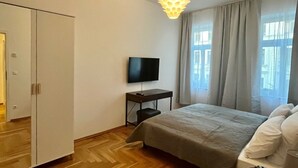 A bedroom with a bed, a TV on a stand, a wardrobe, and a desk with a chair. - Firstclass 2r_apartment (Leipzig)