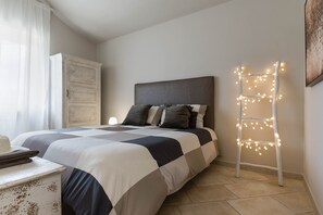 Un dormitorio con una cama, un armario, una escalera con luces y un sombrero sobre una mesa.