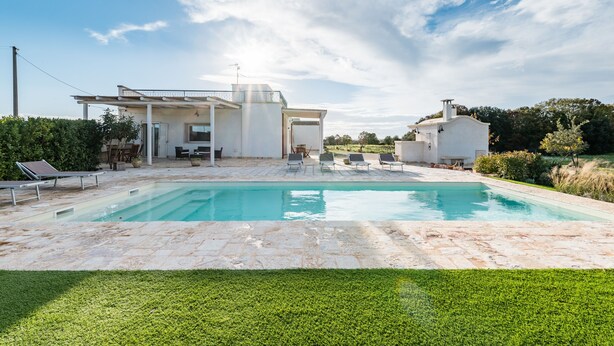 Una casa moderna con piscina, mobiliario exterior y jardín.