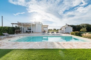 Una casa moderna con piscina, mobiliario exterior y jardín.