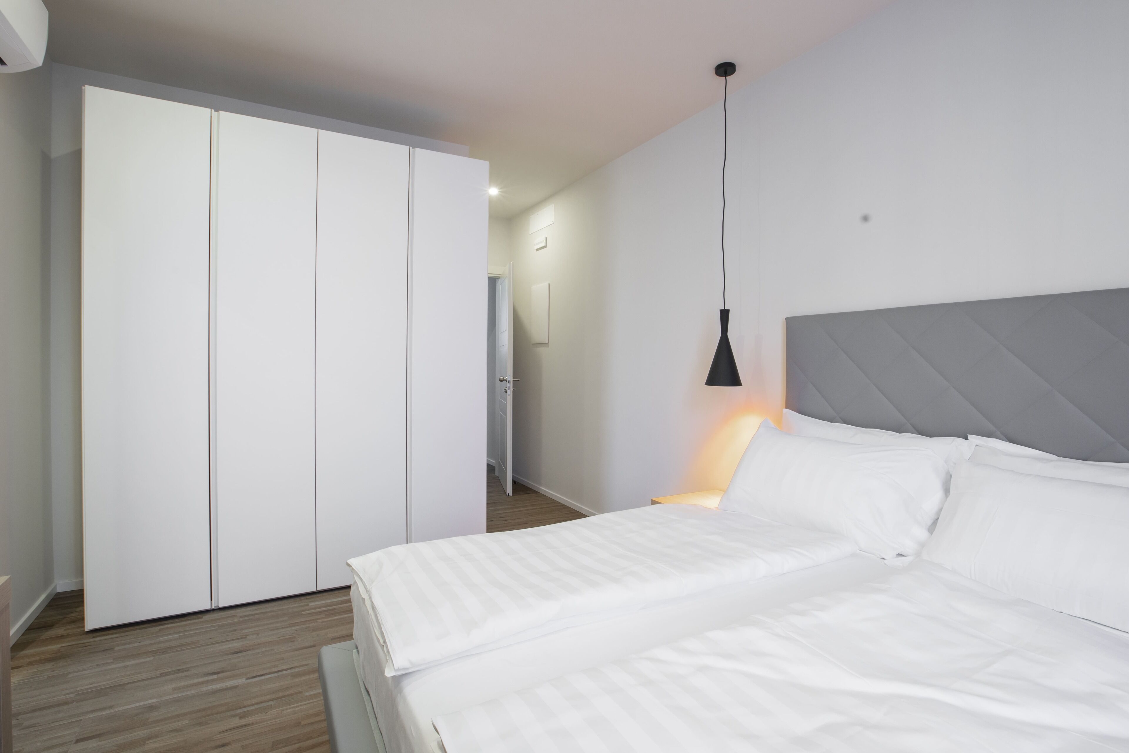 Ein Schlafzimmer mit Bett, Kleiderschrank und einer Pendelleuchte.