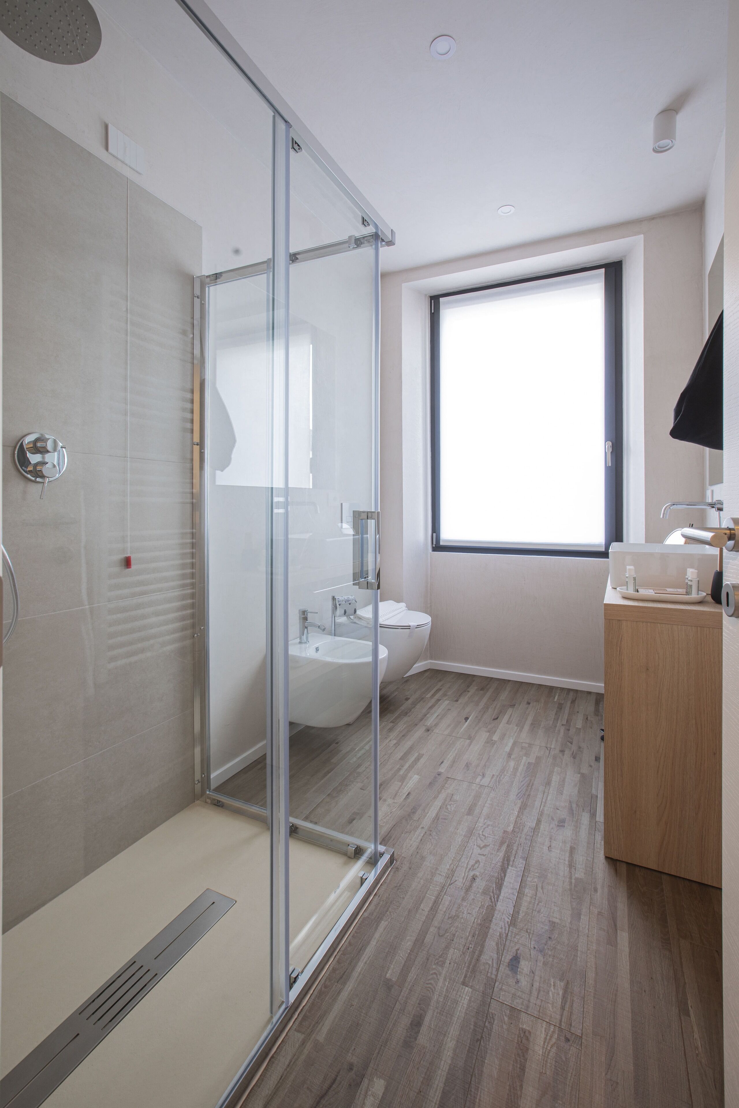 A modern bathroom with a glass shower enclosure, a sink, and a toilet.