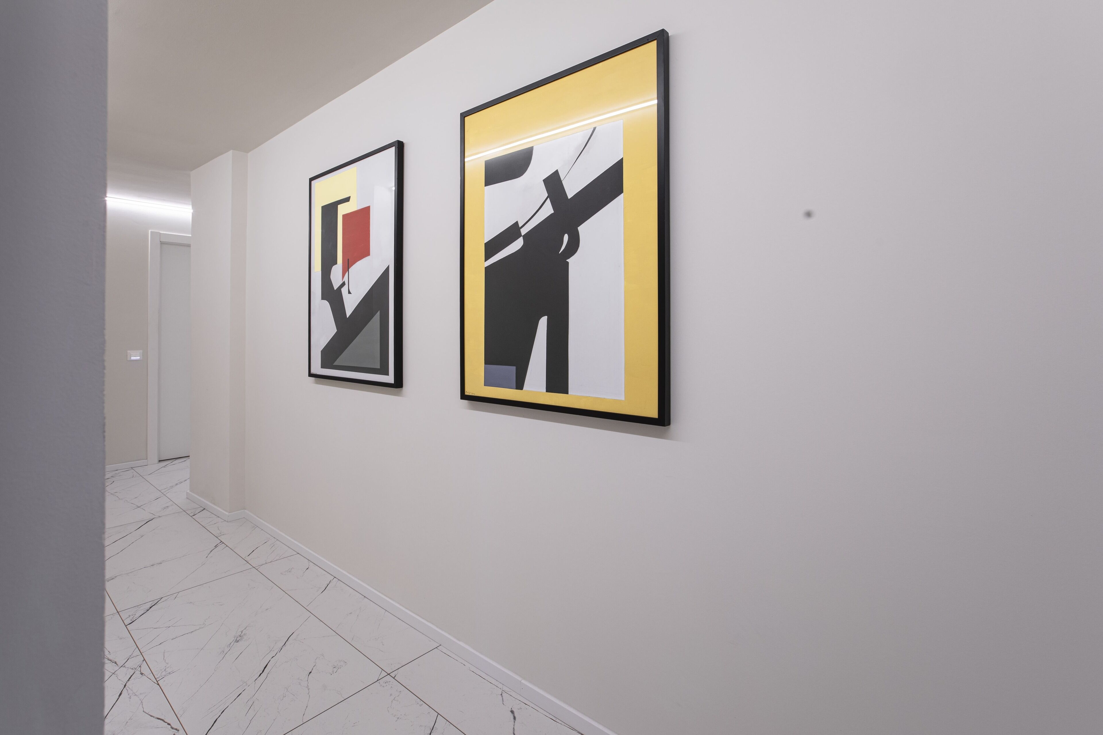 Un pasillo con dos obras de arte enmarcadas en la pared.