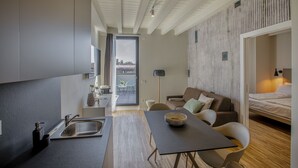 Moderni ja kompakti oleskelutila, jossa on pieni keittiö, ruokailualue ja makuuhuone.