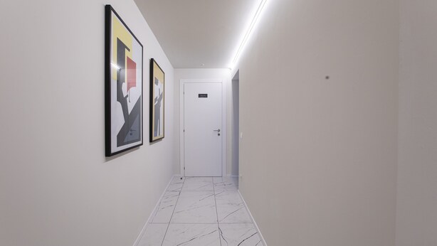 A hallway with white walls, a marble-patterned floor, and two framed artworks. - Ah Villa Glori Brescia (Brescia)