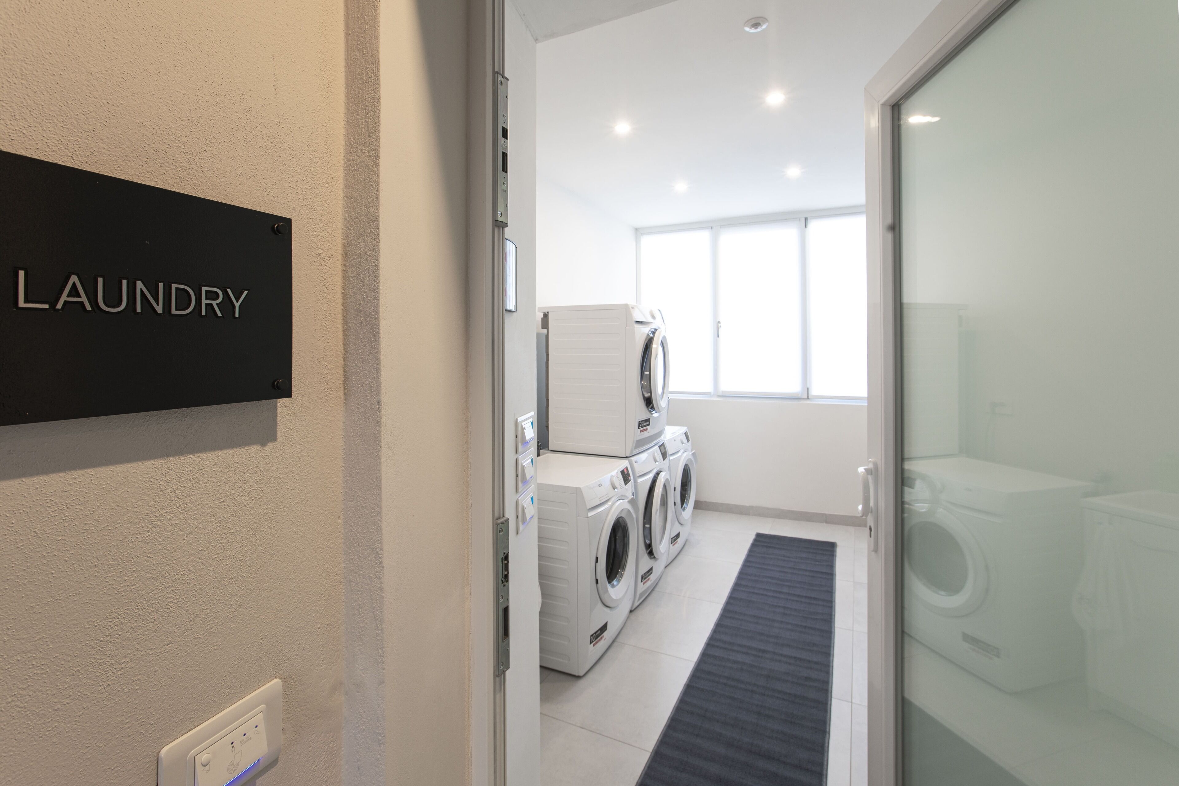 A laundry room with a sign labeled "LAUNDRY" and a row of washing machines.