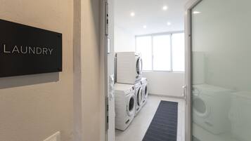 A laundry room with a sign labeled "LAUNDRY" and a row of washing machines.