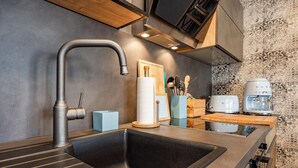 Une cuisine moderne dotée d’un évier en acier inoxydable, d’un plan de travail en bois et d’un crédence ornée de carreaux à motifs.