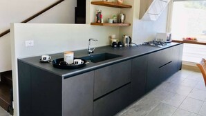 Una cucina moderna con isola centrale, mobili scuri, lavello integrato e una finestra che offre luce naturale.