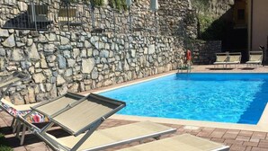 Una piscina con sdraio e un muro in pietra.