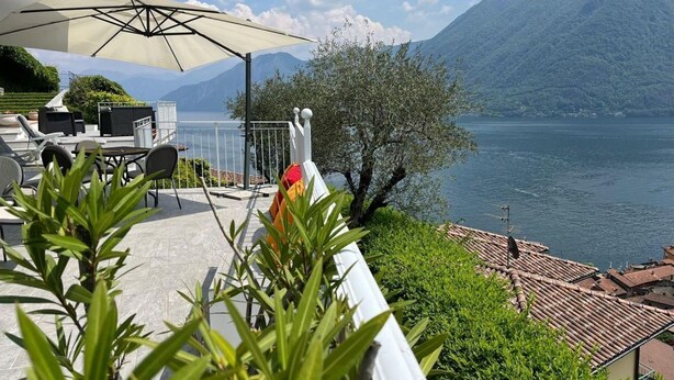 Una terrazza con posti a sedere all'aperto e vista su un lago e montagne.