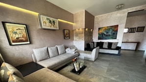 A modern living room with a sectional sofa, a glass coffee table, and a fireplace.