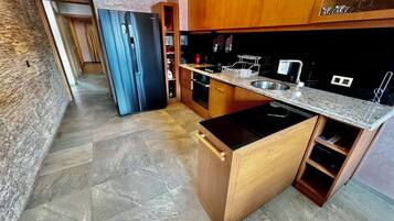 A modern kitchen with a black stove, wooden cabinets, and a granite countertop.