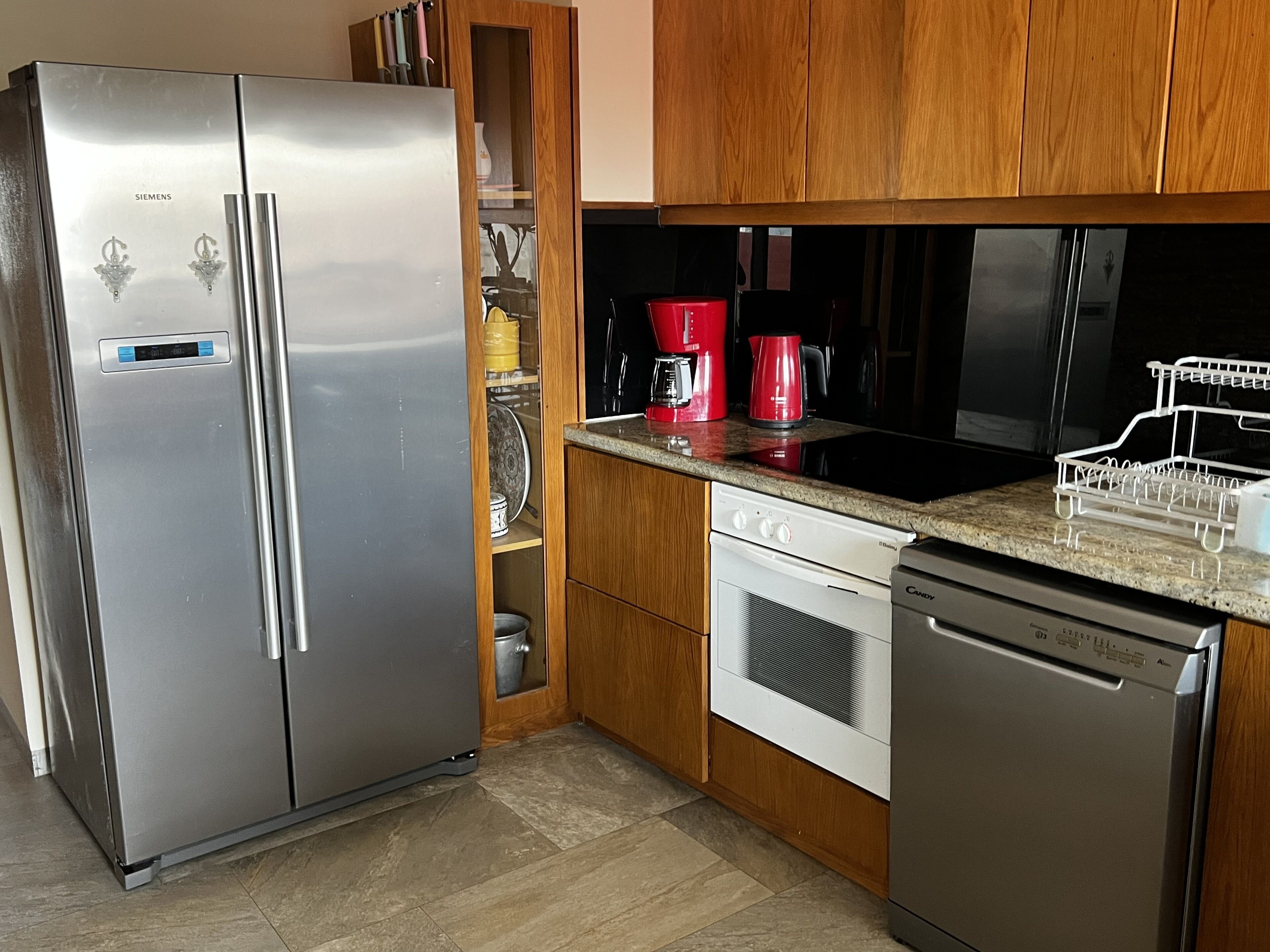 A modern kitchen with a stainless steel refrigerator, a built-in oven, a dishwasher, and a coffee maker.