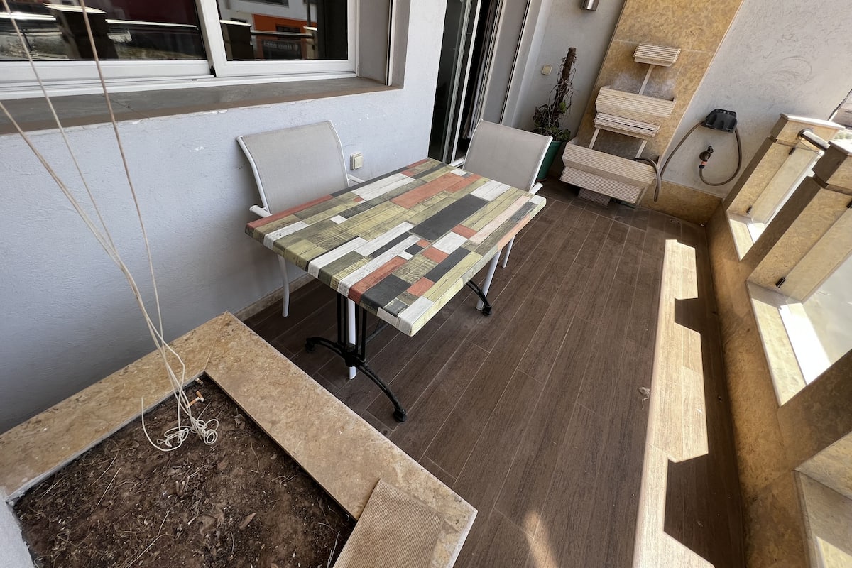 Un espace de bureau moderne avec une table en bois, des chaises blanches et une fenêtre donnant sur des immeubles.