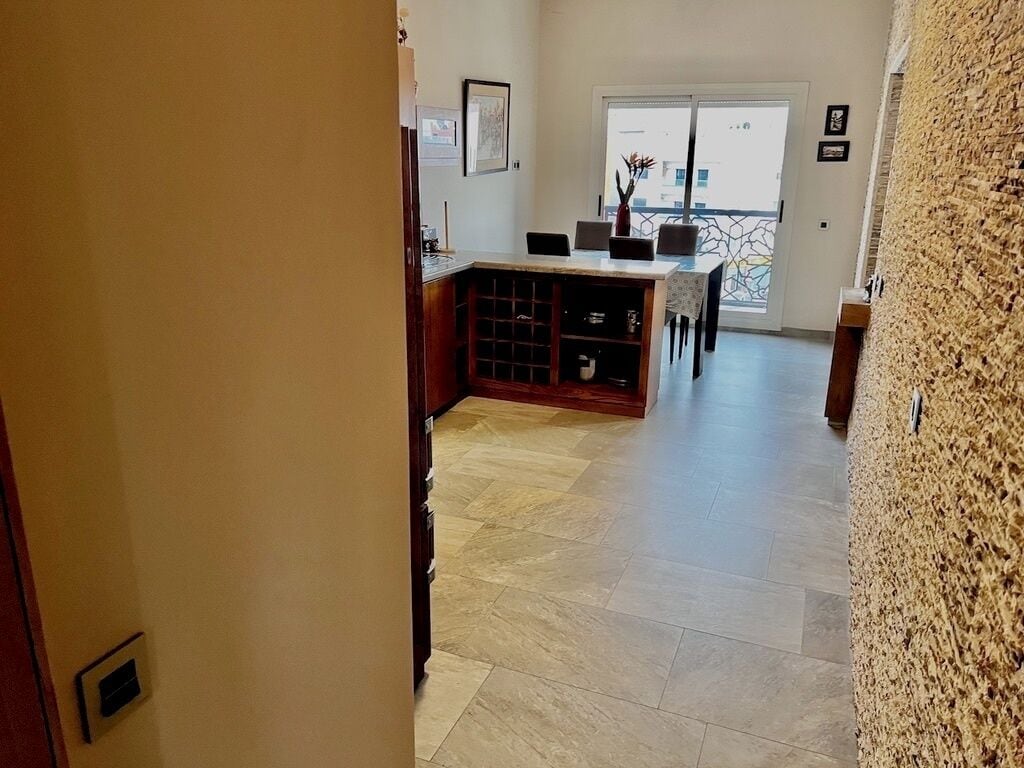 A hallway leading to a dining area with a view of the outside.