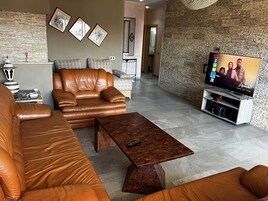 Una sala moderna con un sofá de cuero, una mesa de centro de madera y un televisor sobre un mueble de madera.