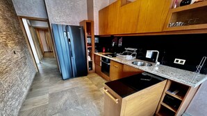 A modern kitchen with a built-in oven, a stainless steel sink, and wooden cabinetry.