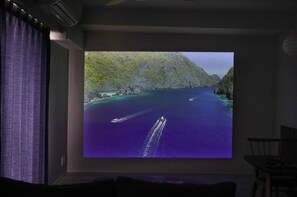 Une pièce dotée d’un grand écran diffusant une vue panoramique d’une zone côtière avec des bateaux.