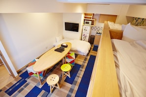 Compact room with a single bed, desk, and TV, offering basic amenities like a microwave and refrigerator.