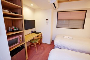 Cozy retreat with a single bed, desk, and microwave.