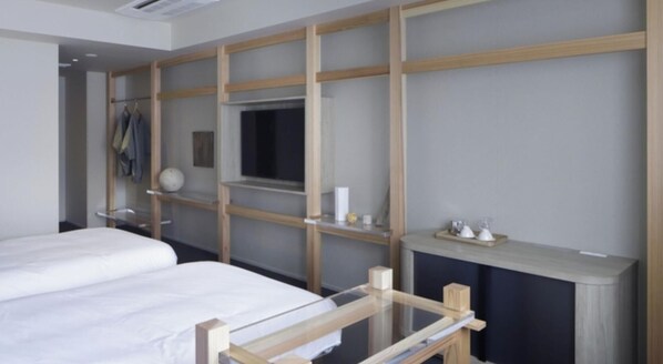 Una camera d'albergo con un letto, un armadio, uno specchio e uno scaffale con articoli da toilette.