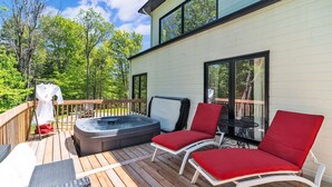 Eine Terrasse mit Whirlpool, zwei roten Sitzgelegenheiten und einem Tisch.