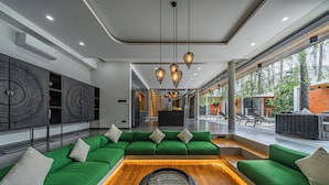 Un interior moderno con un conjunto de sofá verde, una mesa de centro de madera e iluminación colgante.