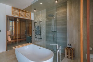 Un baño moderno con una bañera independiente, ducha con mampara de vidrio y un banco de madera.