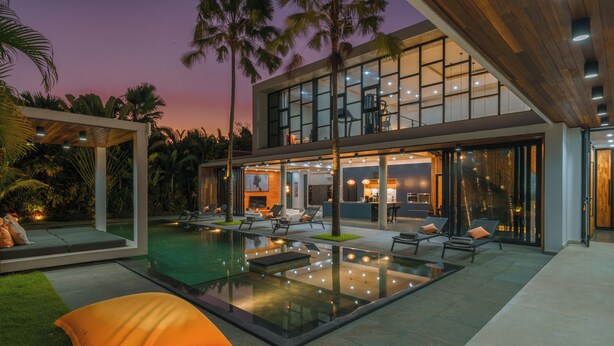 Una casa moderna con piscina, mobiliario de exterior y un amplio ventanal.