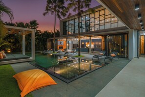 A modern house with a swimming pool, outdoor seating, and a large glass facade. - Villa Aless (Canggu)