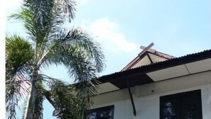 A two-story house with a white exterior, a dark roof, and a black gate.