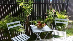 A small outdoor seating area with a white metal table and two white metal chairs.